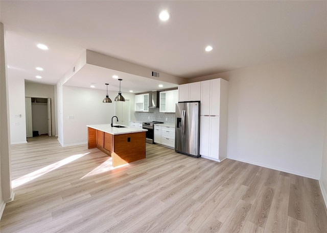 kitchen featuring a sink, stainless steel appliances, light countertops, wall chimney exhaust hood, and backsplash