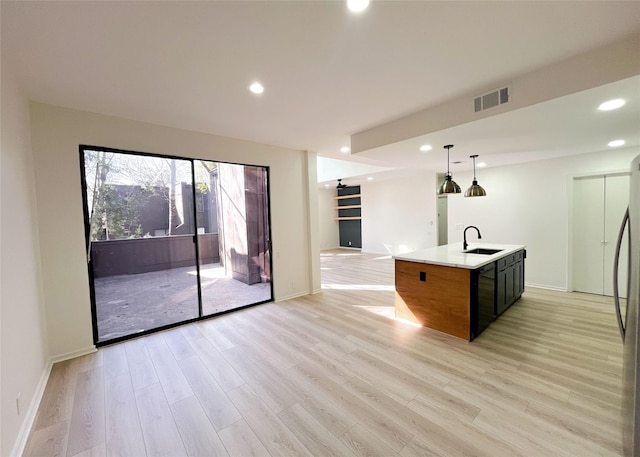 kitchen with open floor plan, light wood-type flooring, visible vents, and a sink