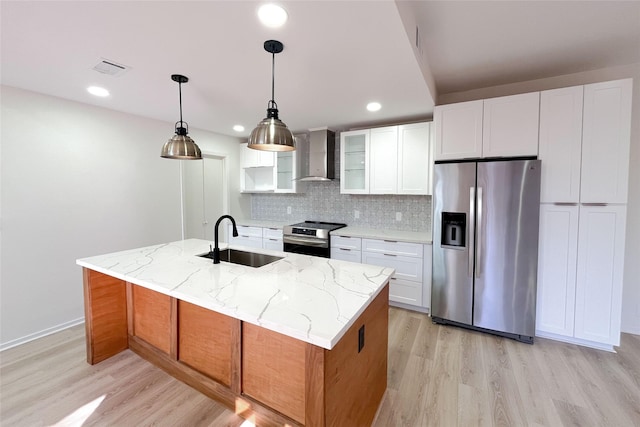 kitchen with backsplash, wall chimney range hood, light wood-style flooring, stainless steel appliances, and a sink