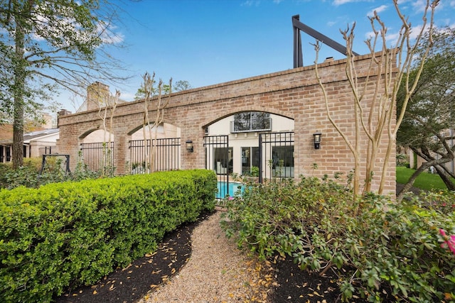 back of house featuring brick siding and fence