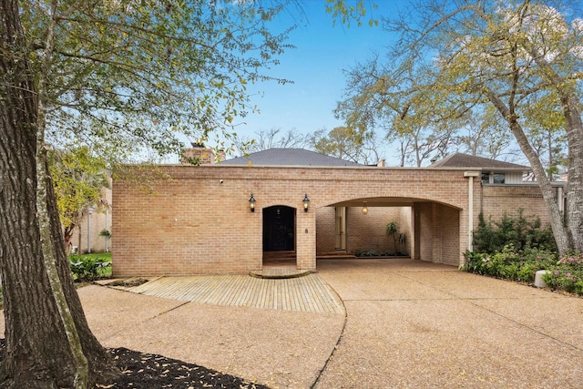 view of front facade with brick siding, driveway, and a chimney