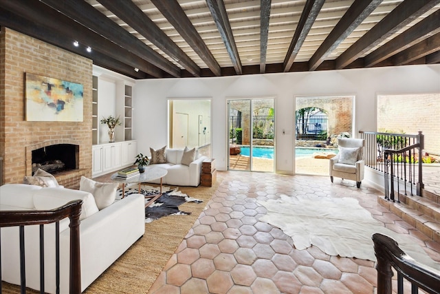 living area featuring built in features, beamed ceiling, and a brick fireplace