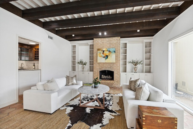 living area with beamed ceiling and a brick fireplace