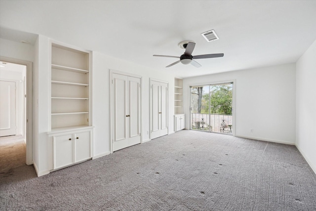 unfurnished bedroom with carpet, baseboards, visible vents, ceiling fan, and multiple closets