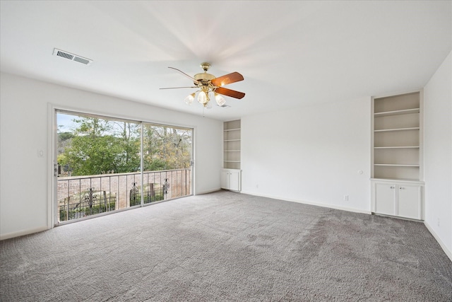 empty room with visible vents, baseboards, carpet, built in features, and a ceiling fan