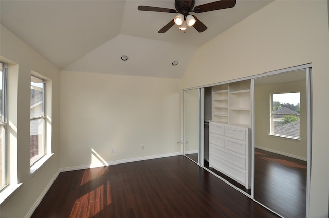 unfurnished bedroom with lofted ceiling, a closet, dark wood-style floors, and baseboards