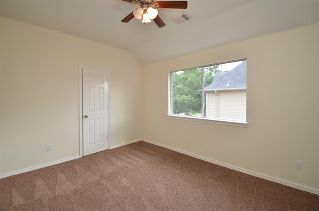 spare room featuring carpet floors, visible vents, a ceiling fan, vaulted ceiling, and baseboards