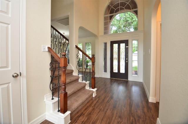 entrance foyer with a healthy amount of sunlight, a towering ceiling, baseboards, and wood finished floors