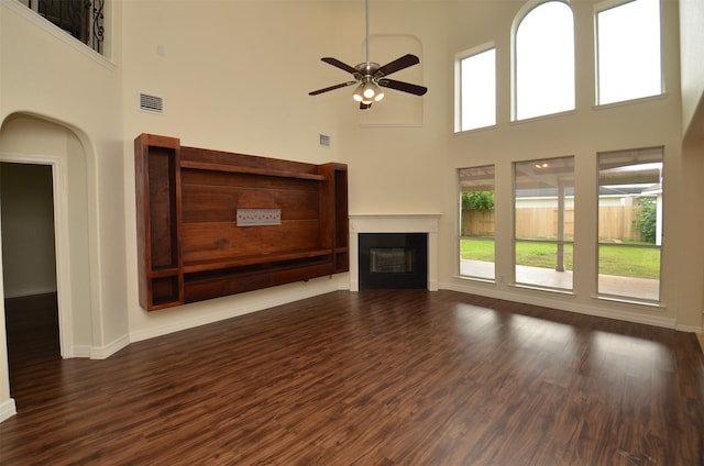 unfurnished living room featuring a ceiling fan, a glass covered fireplace, visible vents, and wood finished floors