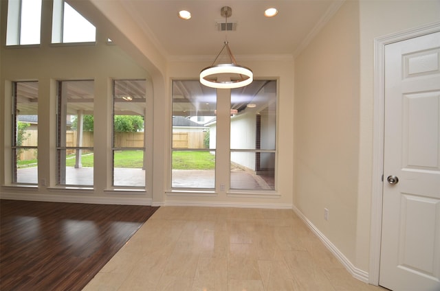 doorway featuring baseboards, plenty of natural light, visible vents, and crown molding