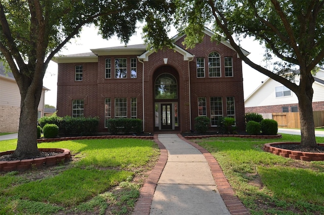 traditional-style house with fence, a front lawn, french doors, and brick siding