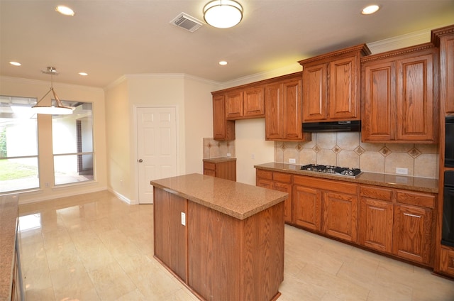 kitchen with a center island, brown cabinets, visible vents, stainless steel gas stovetop, and under cabinet range hood