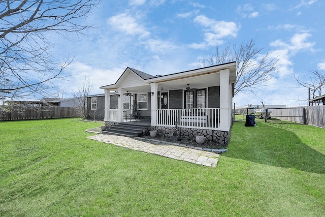 exterior space with covered porch, ceiling fan, a fenced backyard, and a yard