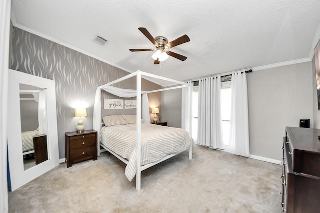 carpeted bedroom featuring baseboards, visible vents, a ceiling fan, a textured ceiling, and crown molding