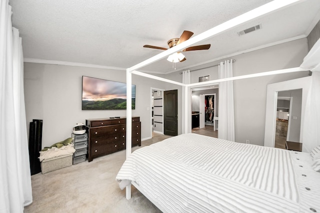 carpeted bedroom featuring a textured ceiling, ornamental molding, visible vents, and a ceiling fan