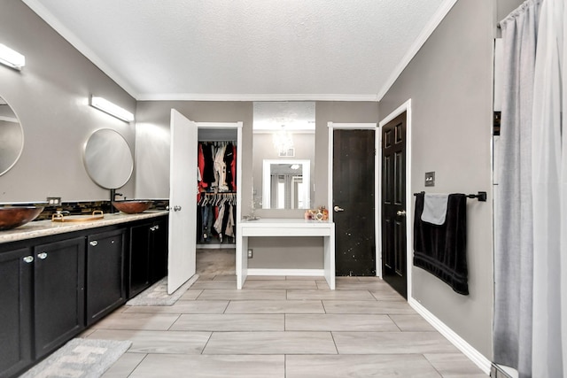 bathroom featuring ornamental molding, baseboards, vanity, and a textured ceiling