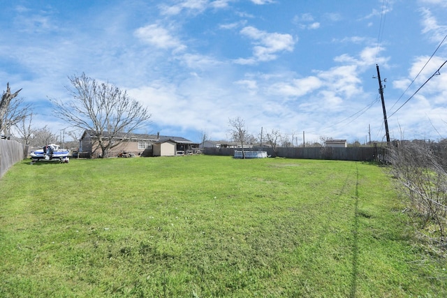 view of yard with an outbuilding, fence, and a storage unit