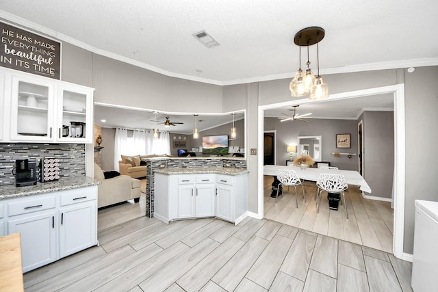 kitchen featuring white cabinets, crown molding, open floor plan, and decorative backsplash