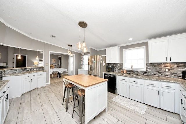 kitchen with black dishwasher, stainless steel fridge with ice dispenser, vaulted ceiling, white cabinetry, and a sink