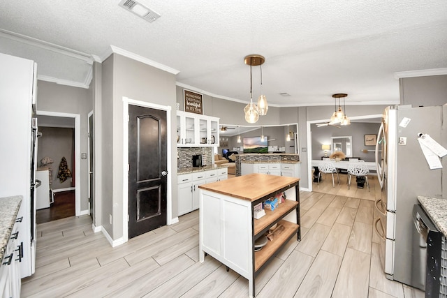 kitchen with stainless steel appliances, visible vents, wooden counters, wood tiled floor, and white cabinets