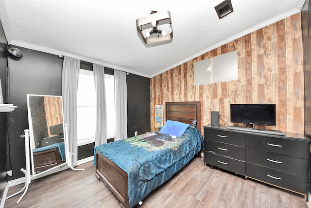 bedroom featuring ornamental molding, light wood-type flooring, and vaulted ceiling