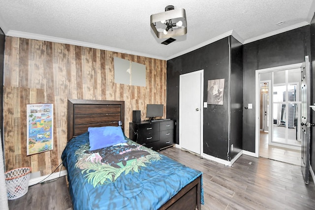 bedroom with a textured ceiling, baseboards, crown molding, and wood finished floors