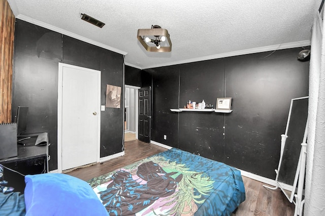 bedroom with a textured ceiling, wood finished floors, visible vents, baseboards, and ornamental molding