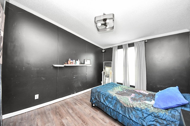 bedroom with a textured ceiling, ornamental molding, and wood finished floors