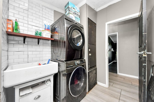 laundry room with a textured ceiling, laundry area, stacked washer / dryer, ornamental molding, and wood tiled floor