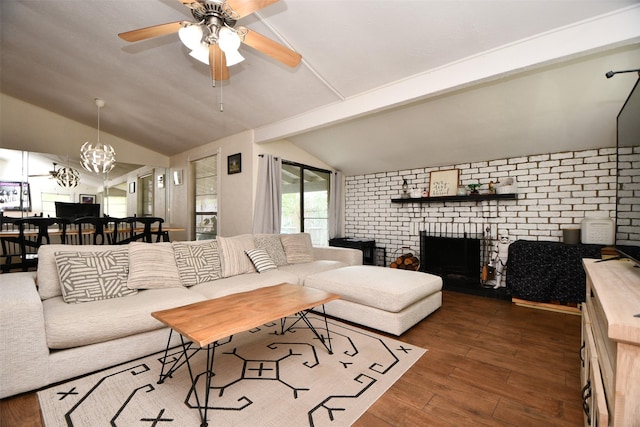 living area featuring lofted ceiling with beams, a brick fireplace, wood finished floors, and ceiling fan with notable chandelier