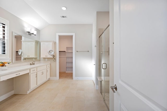 bathroom featuring vanity, visible vents, baseboards, a shower stall, and a walk in closet