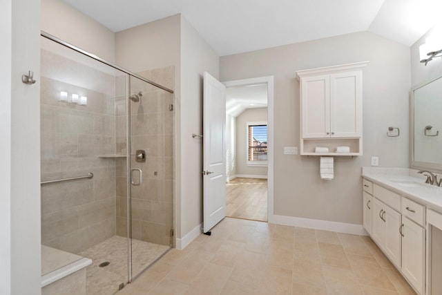 full bath with a stall shower, vanity, baseboards, and vaulted ceiling