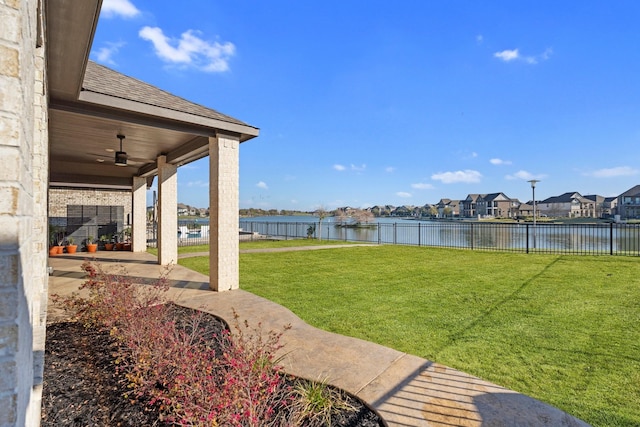 view of yard featuring a residential view, a water view, ceiling fan, and fence