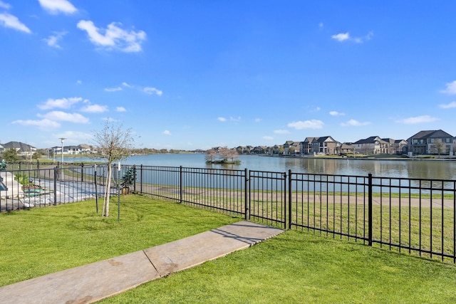 view of yard with fence, a residential view, and a water view