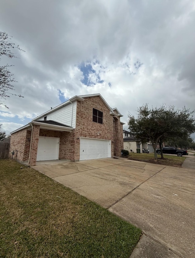 view of side of property with brick siding, driveway, an attached garage, and a yard