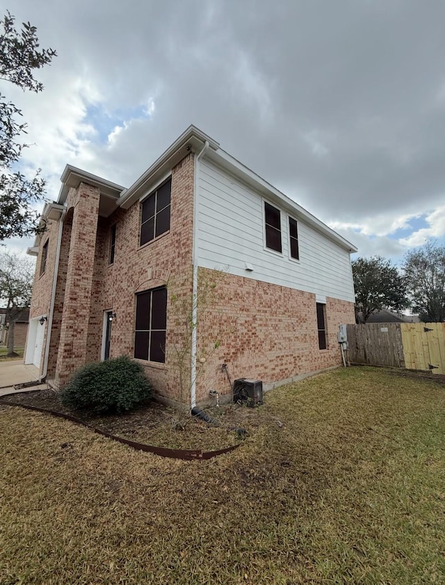 view of home's exterior with fence, brick siding, and a lawn