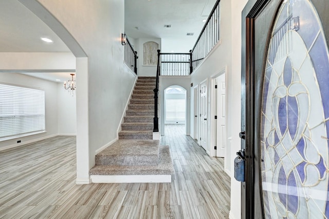 entrance foyer with stairway, baseboards, arched walkways, and wood finished floors