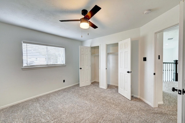 unfurnished bedroom with baseboards, ceiling fan, carpet flooring, and multiple closets