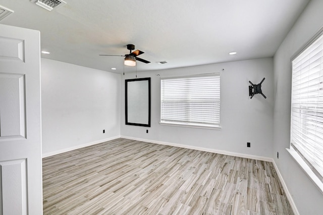 empty room featuring light wood-type flooring, baseboards, visible vents, and a wealth of natural light