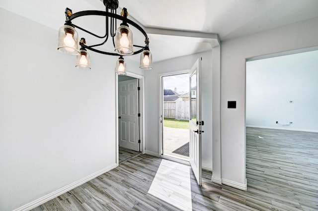 entryway with a chandelier, wood finished floors, and baseboards