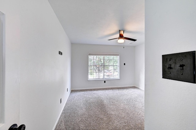 carpeted spare room featuring baseboards and a ceiling fan