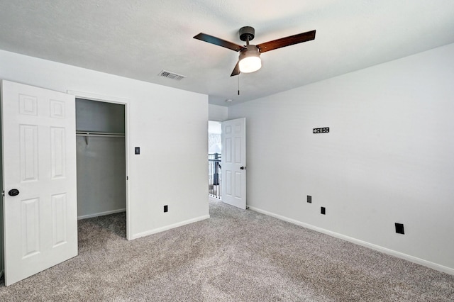 unfurnished bedroom featuring carpet, a walk in closet, a closet, visible vents, and baseboards