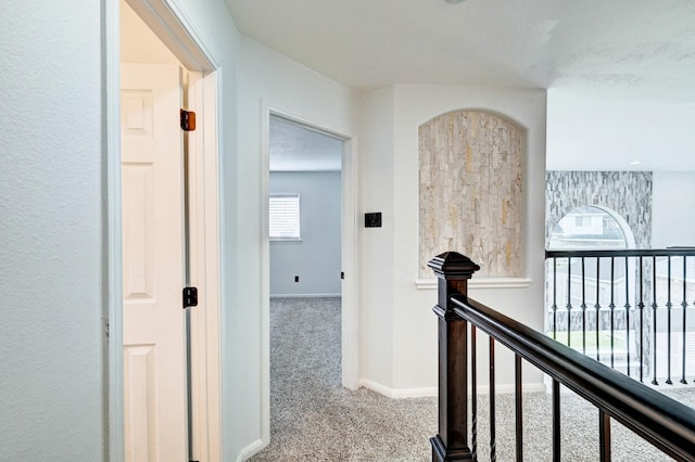 corridor featuring carpet, baseboards, and an upstairs landing