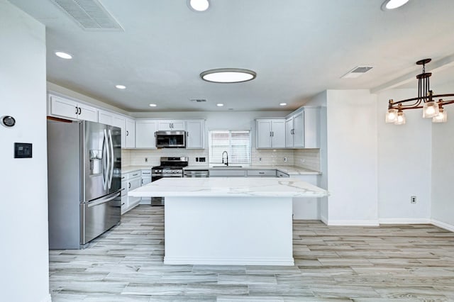 kitchen with white cabinetry, visible vents, appliances with stainless steel finishes, decorative backsplash, and light stone countertops