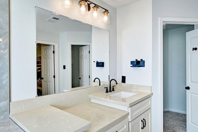 bathroom featuring a walk in closet, visible vents, vanity, and baseboards