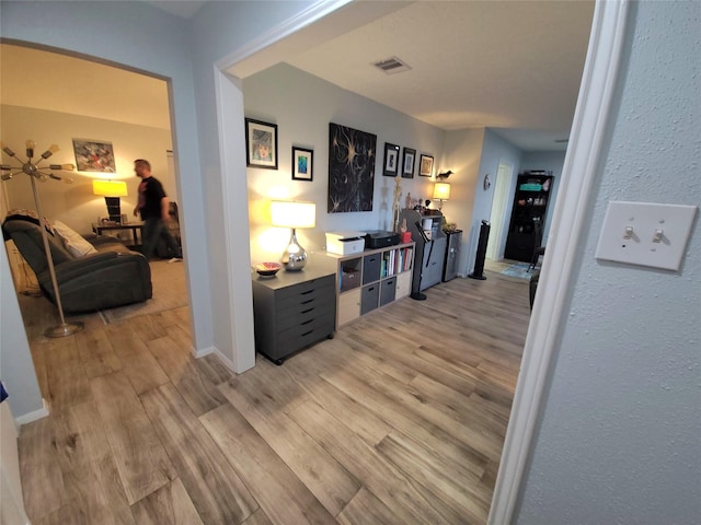 hall with visible vents, light wood-type flooring, and baseboards