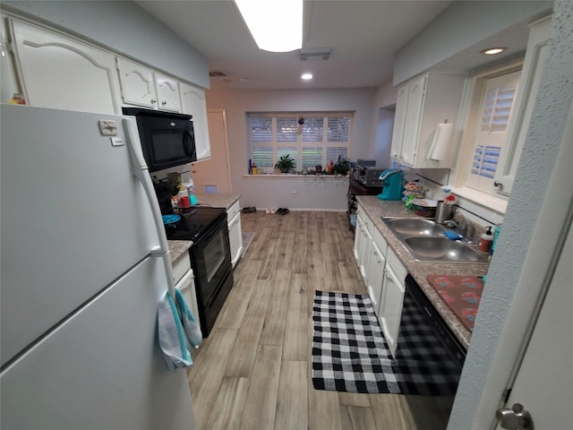 kitchen with white cabinetry, black appliances, and a sink