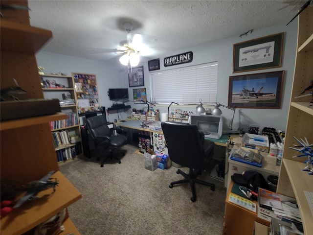 home office featuring a ceiling fan, carpet floors, and a textured ceiling