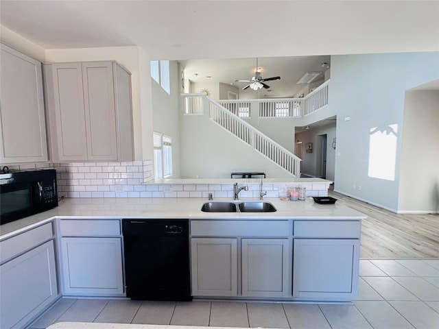 kitchen featuring gray cabinets, a sink, a peninsula, and black appliances