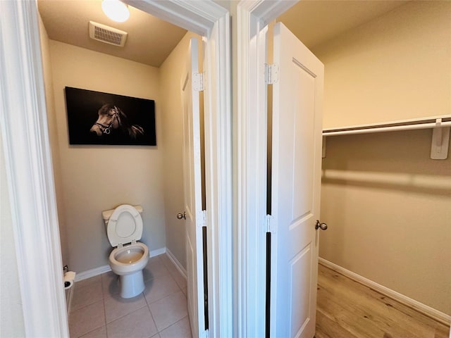 bathroom featuring tile patterned flooring, visible vents, toilet, and baseboards